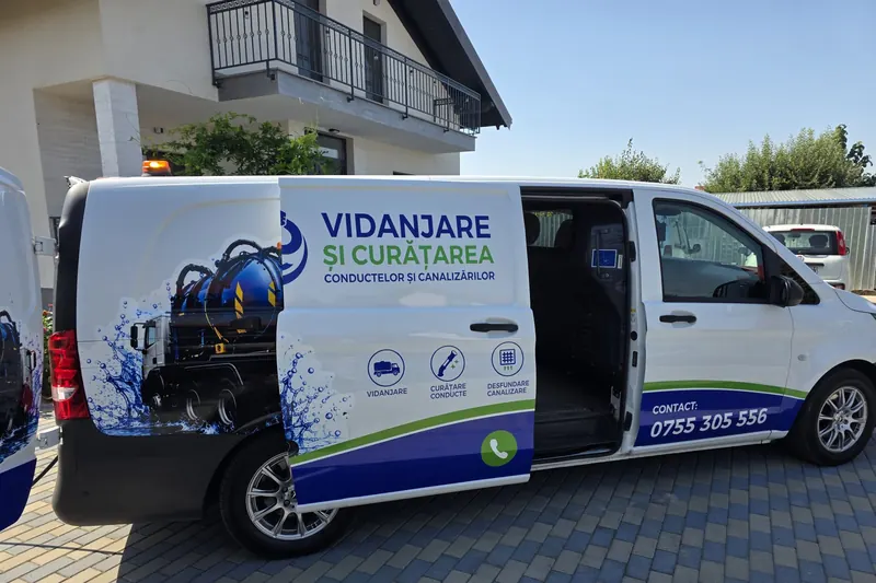 Autoutilitara cu ușa laterală deschisă, parcată la o casă